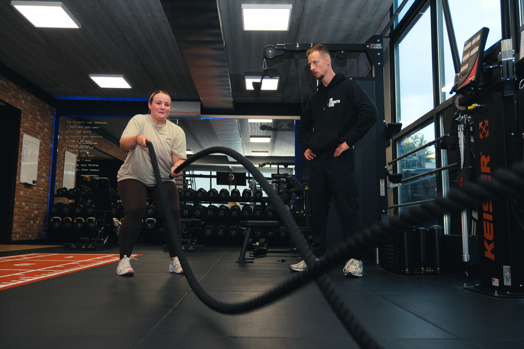 Sporter traint met battle ropes onder begeleiding van een personal trainer