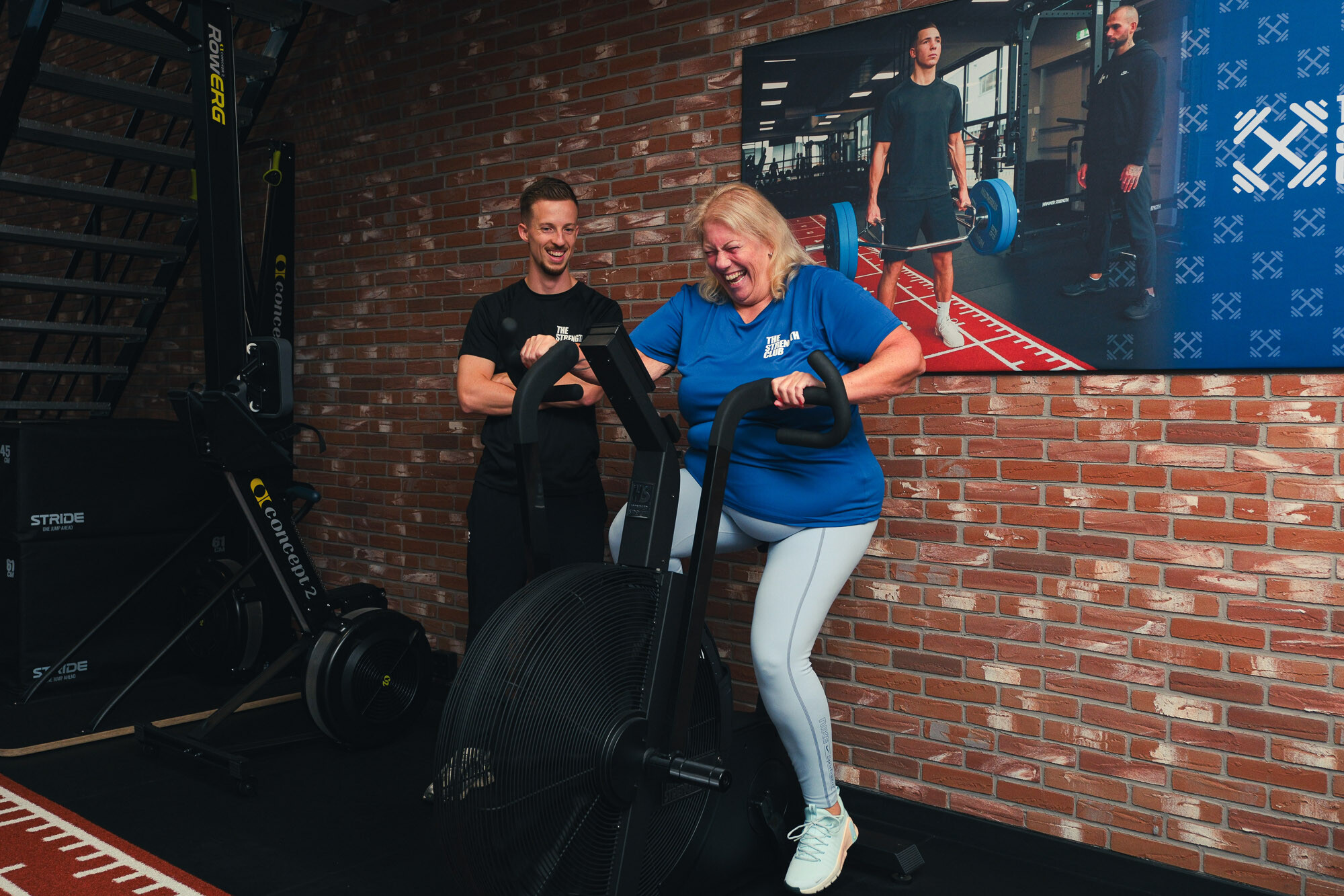 Sporter traint op een airbike onder begeleiding van een personal trainer