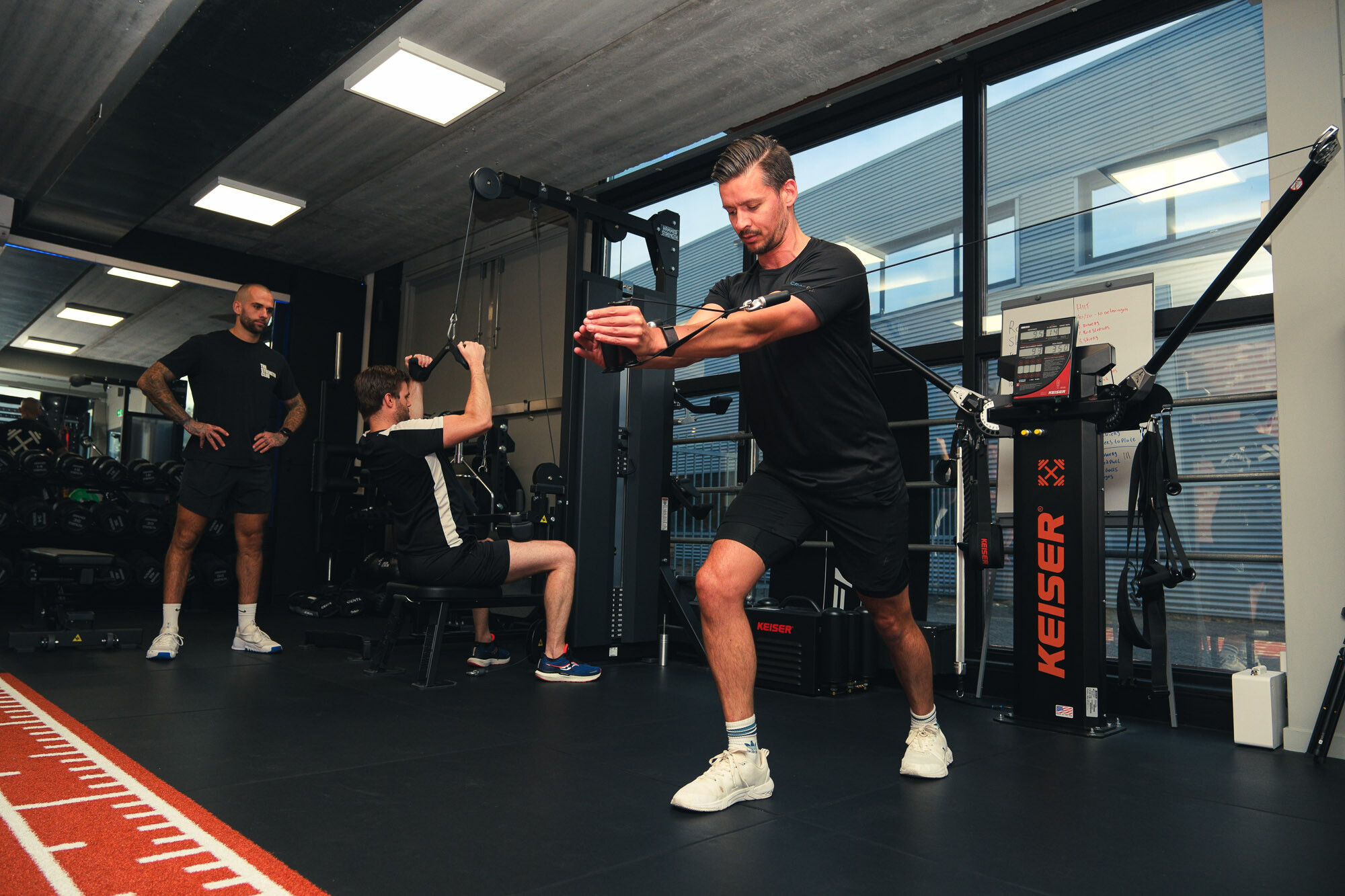 Duo personal training waarbij één sporter een chest fly doet en de ander een lat pulldown Duo personal training waarbij één sporter een chest fly doet en de ander een lat pulldown