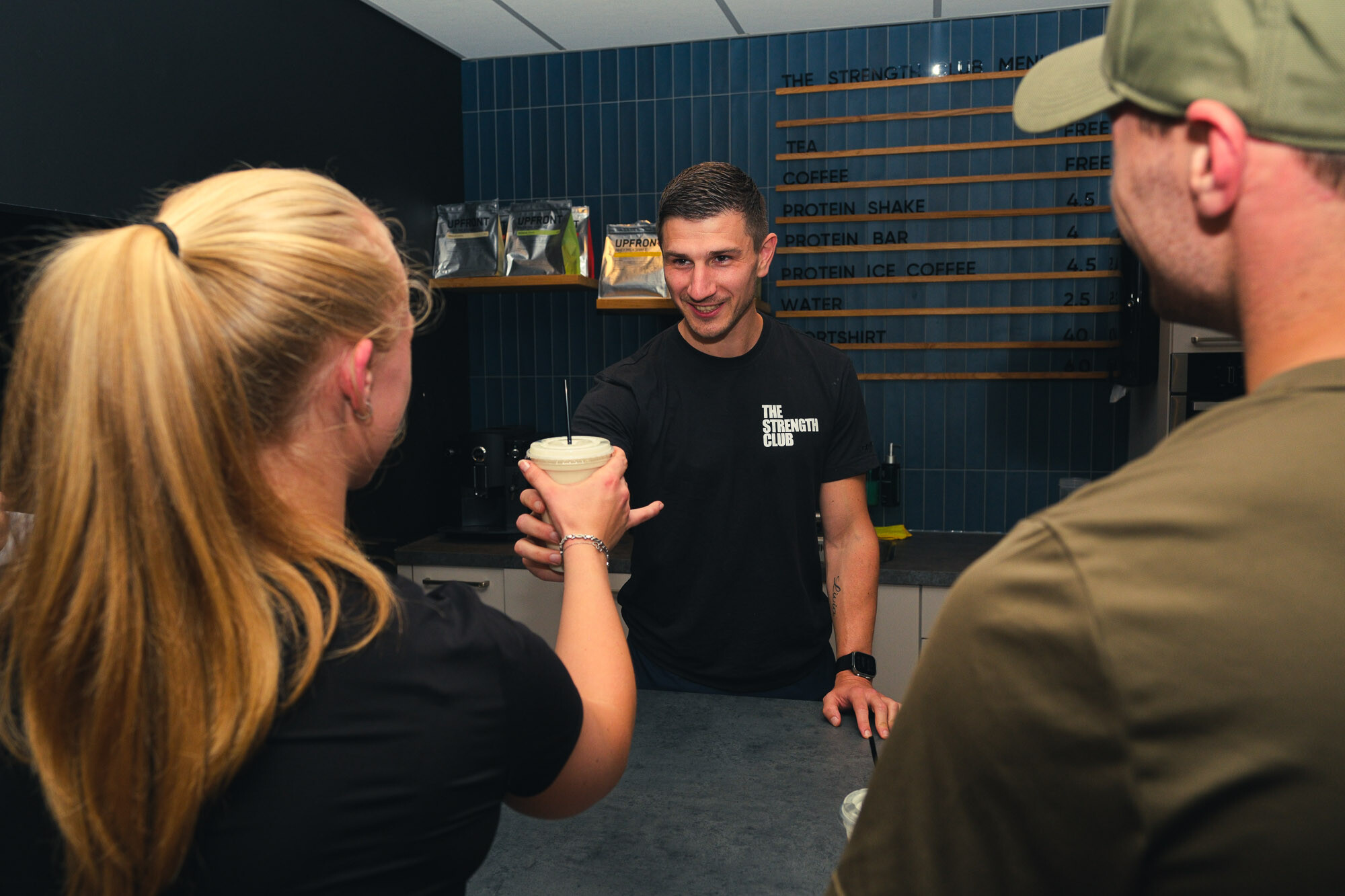 Twee sporters in gesprek met een personal trainer aan de bar