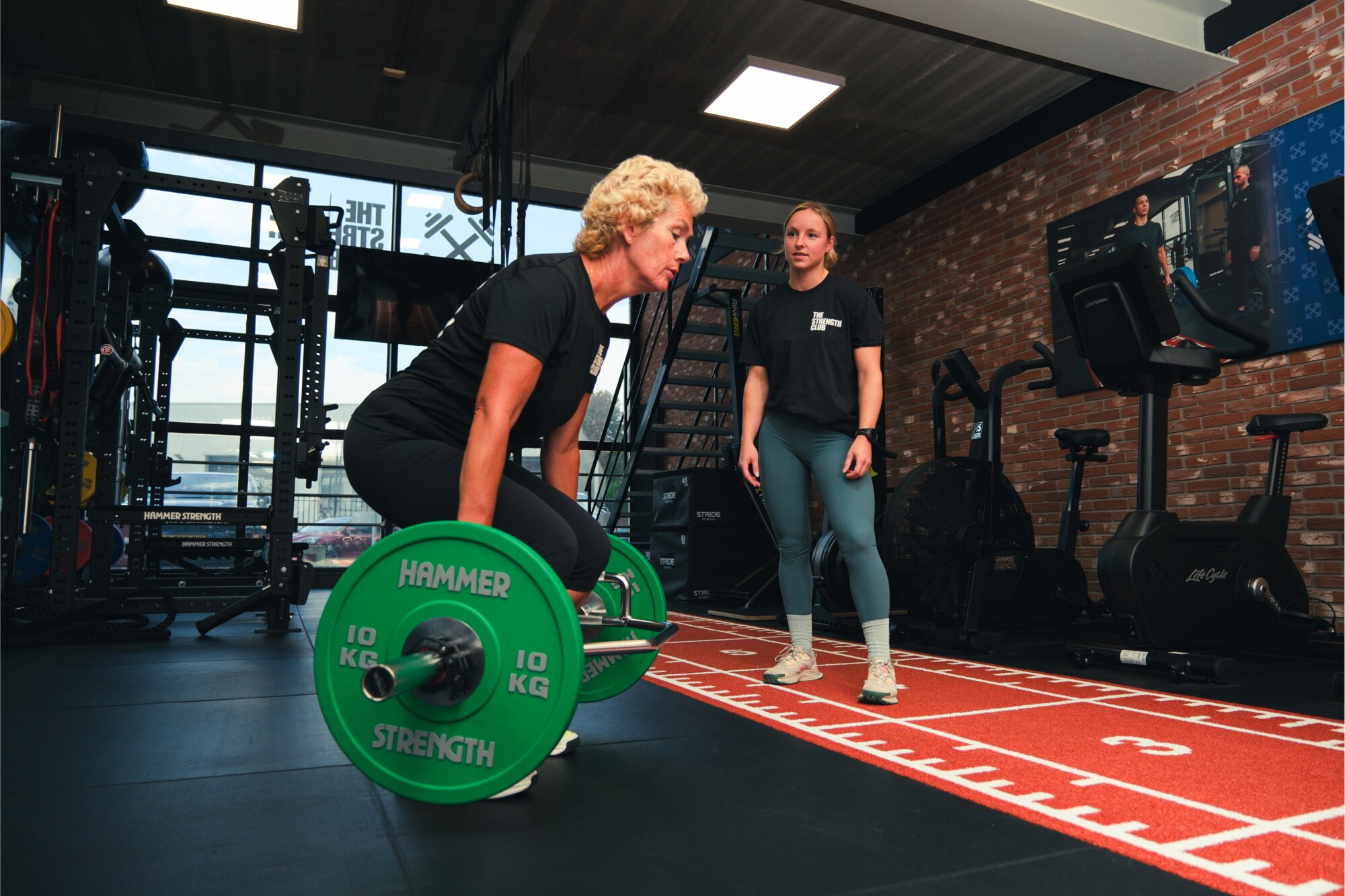 Sporter doet een deadlift met een halterstang onder begeleiding