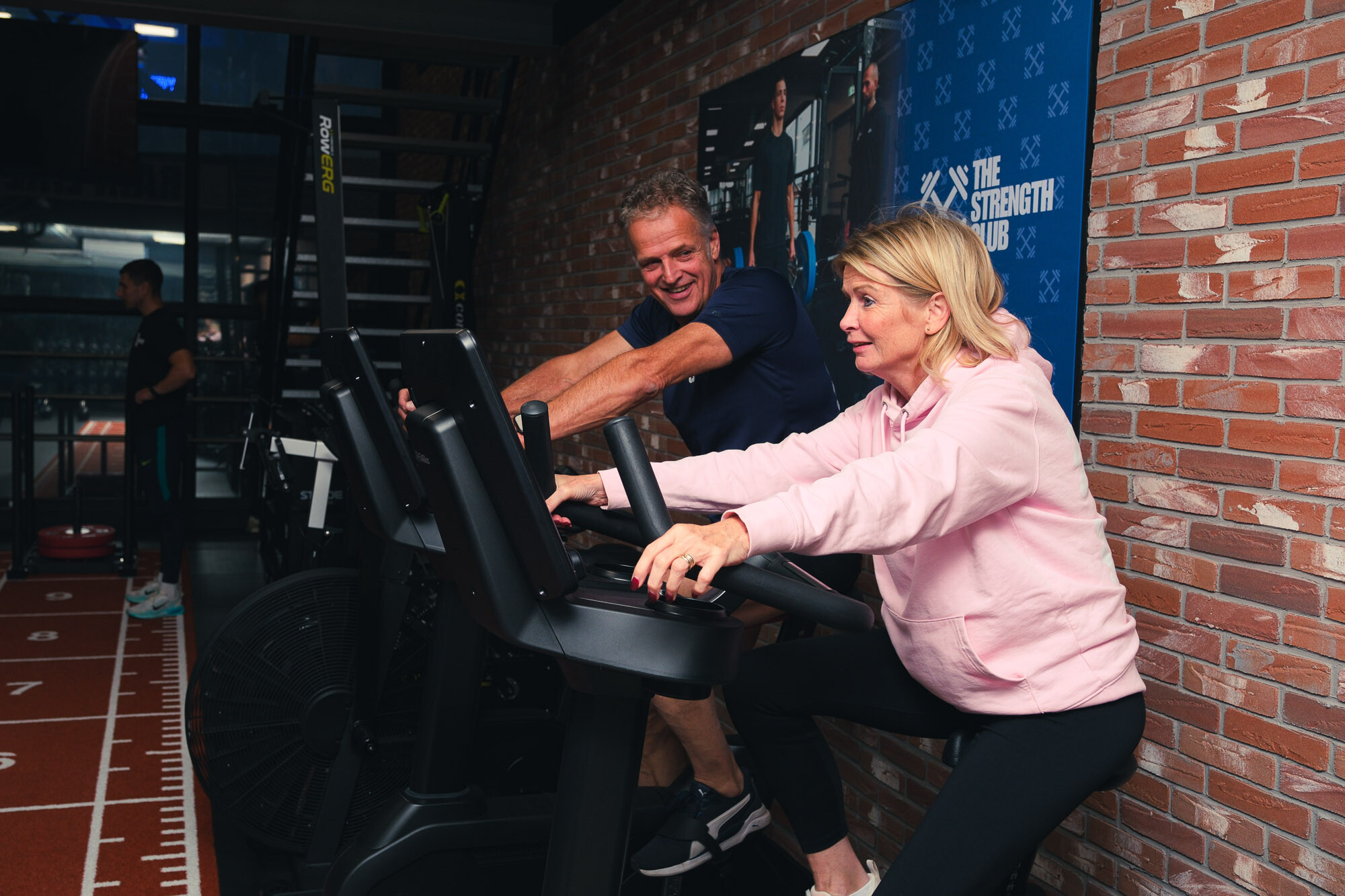 Twee sporters trainen naast elkaar op cardiotoestellen