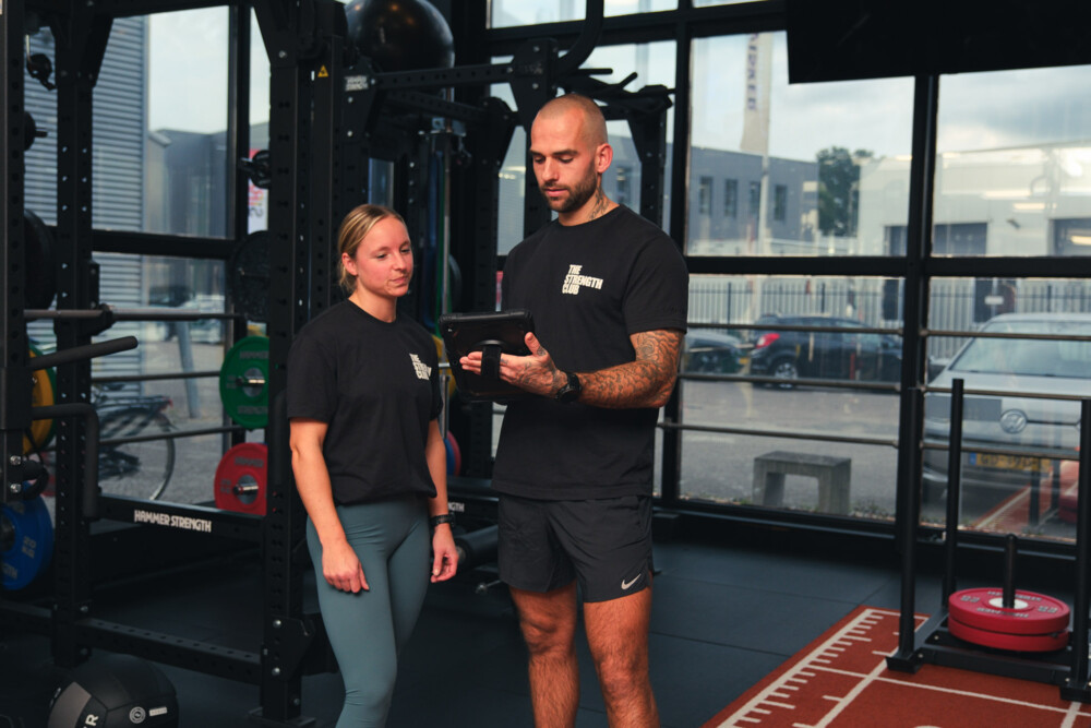 Personal trainer bespreekt gegevens op een tablet met een sporter