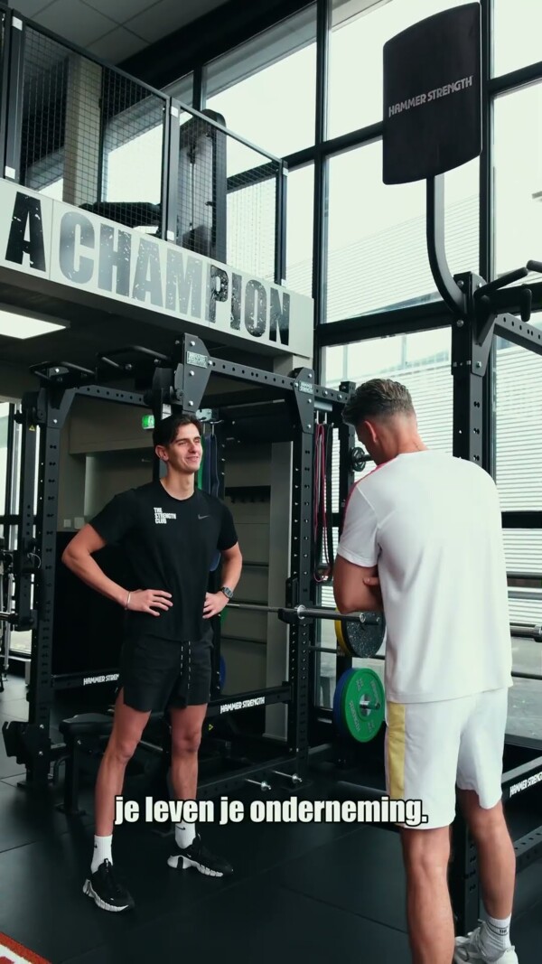 Personal trainer en sporter in gesprek bij een trainingsrek Personal trainer en sporter in gesprek bij een trainingsrek