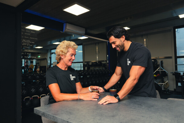 Personal trainer en sporter in gesprek aan de bar Personal trainer en sporter in gesprek aan de bar