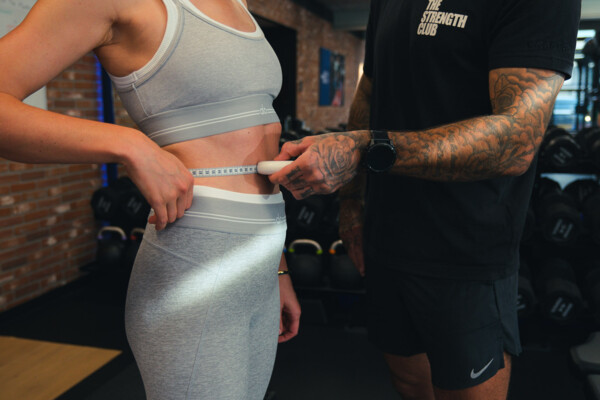 Personal trainer meet de tailleomtrek van een sporter