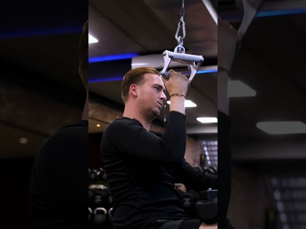 Sporter doet een lat pulldown tijdens bedrijfsfitness Sporter doet een lat pulldown tijdens bedrijfsfitness